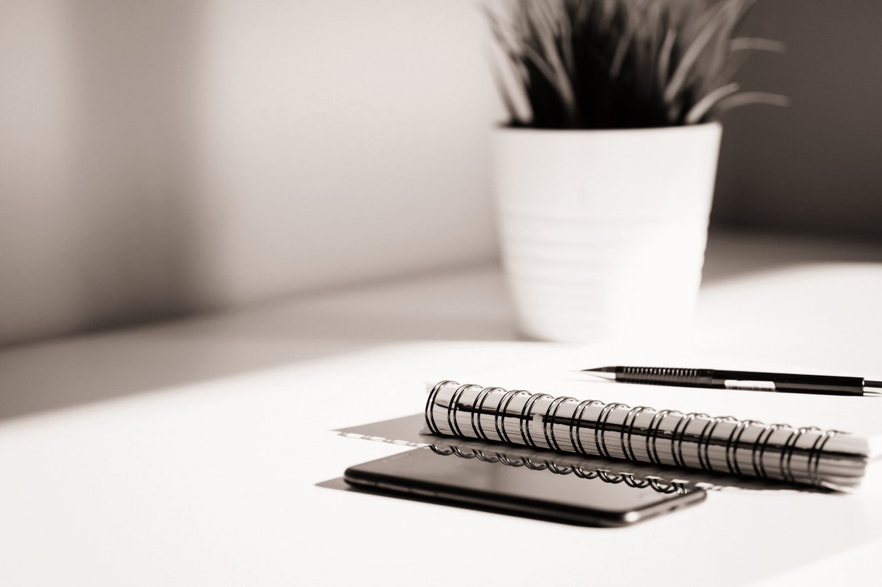 Caderno, caneta e telefone sobre uma mesa