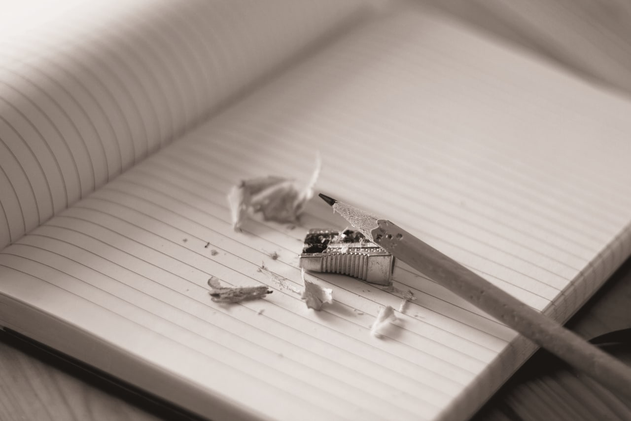 Lápis e apontador sobre um caderno pautado