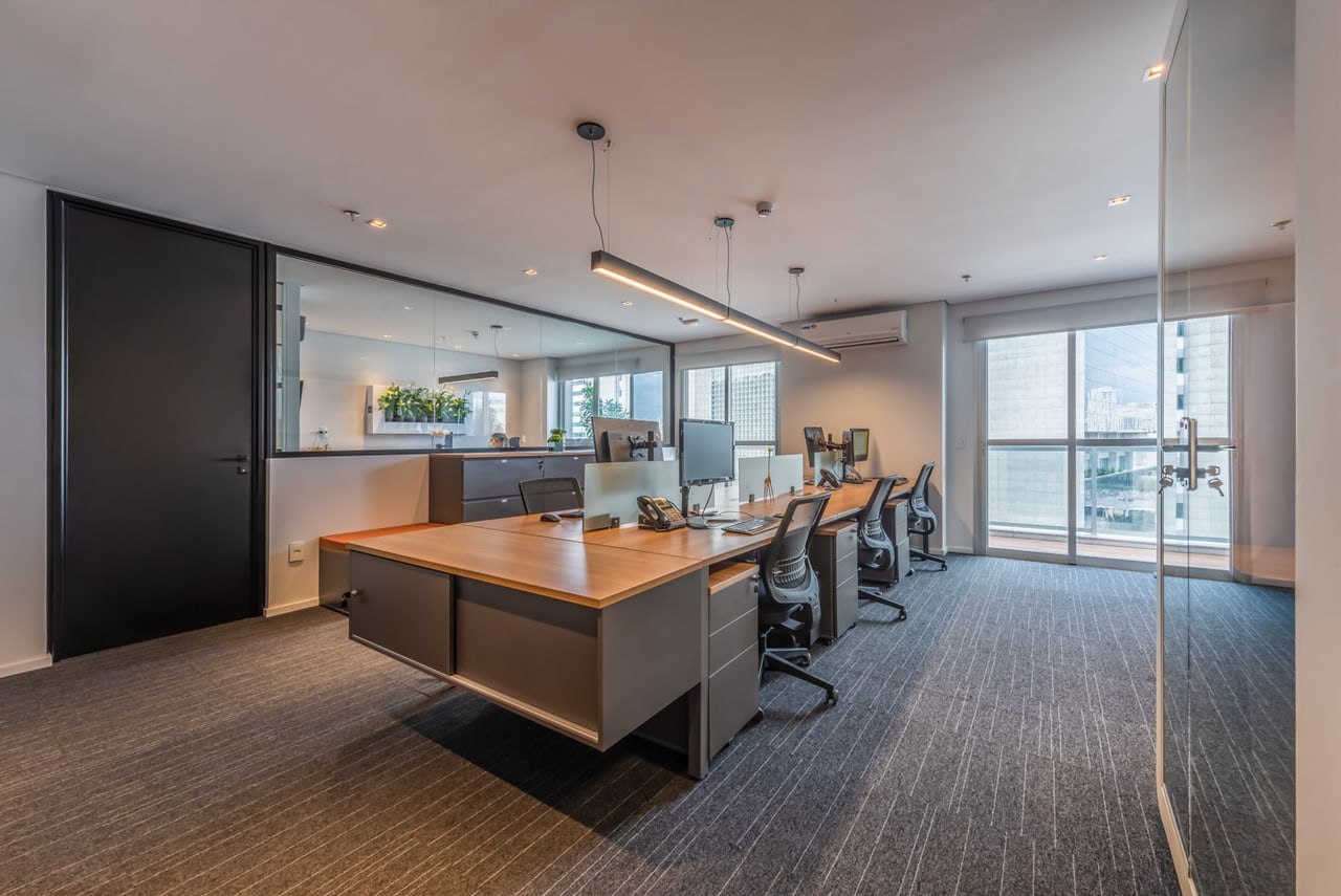 Sala de trabalho do escritório, com mesas e janelas para a cidade